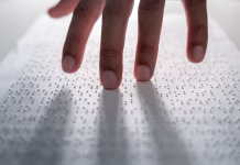 Naredili elektronski vsadek, ki je slepim povrnil vid Hand of a blind person reading some braille text on page paper to learn. Finger of blind student touching the braille alphabet Code on sheet.