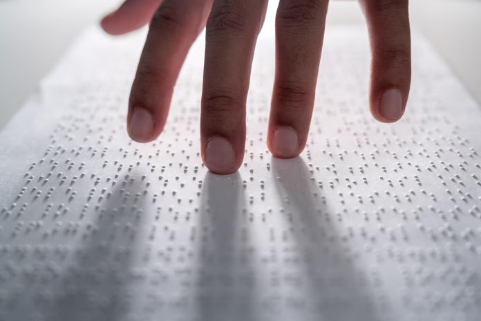 hand-of-a-blind-person-reading-some-braille-text-on-page-paper-to-learn-finger-of-blind-student-touching-the-braille-alphabet-code-on-sheet-stockpack-istock Hand of a blind person reading some braille text on page paper to learn. Finger of blind student touching the braille alphabet Code on sheet.