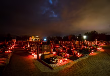 Pri Žalah bo kaos! Preberite te nasvete, da se mu izognete Ljubljana, Slovenia - November 1, 2012: Candles and lantern burning on graves at Cemetery at night for a catholic - christian holiday All Saints' Day. Solemnity of All Saints. All Hallows eve. November  1st. Feast of All Saints. Hallowmas. All Souls' Day.