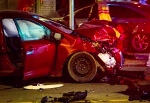 Več kot 40 % umrlih voznikov je imelo v krvi … Nighttime scene showing a serious collision between two cars on a city street with visible damage, debris, and emergency atmosphere under streetlights.