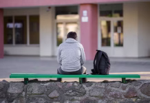 Čez pet let bodo več kot 60 odstotkov prebivalstva mest predstavljali mladi One young man sitting on bench at school yard. Break time. Back view.