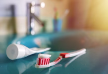 Pravilno ločevanje in recikliranje: kam z zobno ščetko in prazno tubo zobne paste? teeth health: brush and toothpaste on blue sink in bathroom. red toothbrush lies in the interior on background of water tap.