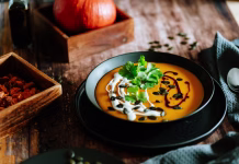 Recept za najbolj okusno jesensko juho Vegetarian, homemade pumpkin cream soup in a bowl on wooden table.