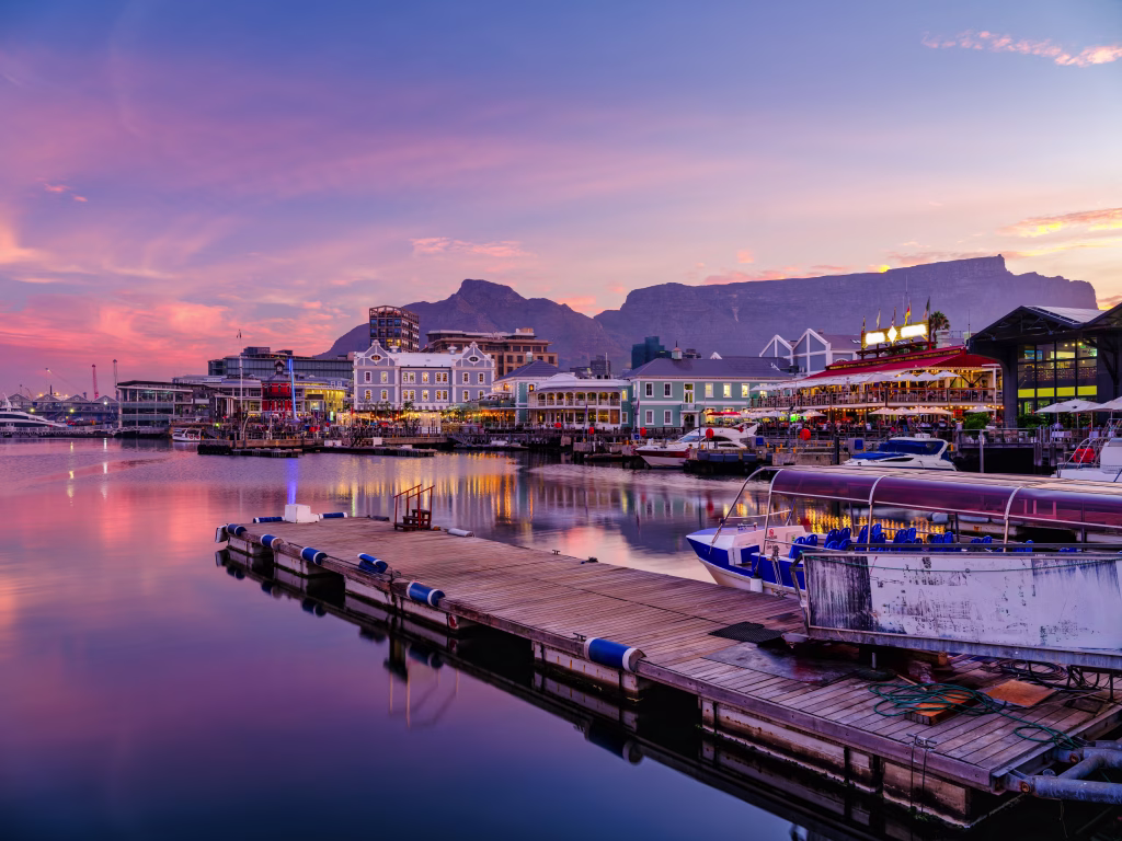 Victoria and Alfred, V and A waterfront lit up during a colorful sunset with table mountain in the background, Cape Town, South Africa