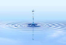 Ali gravitacija povzroča kvantno čudnost? Water drop splash, high resolution 3D rendering. Droplet impact with ripple effect on surface, isolated on blue background. Fluid dynamics, clean water, purity and motion concept. Suitable for eco, hygiene, hydration, and nature visuals