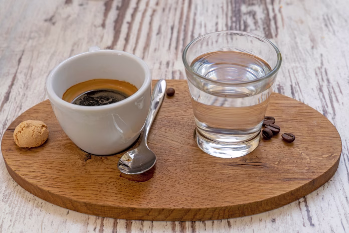 white-cup-of-espresso-and-a-glass-of-water-disposed-on-a-wooden-plate-stockpack-istock White cup of Espresso and a glass of water disposed on a wooden plate