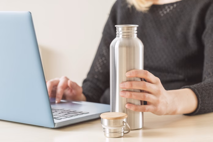 white-woman-holding-her-personal-stainless-steel-water-bottle-on-the-working-table-daily-hydration-habit-to-stay-healthy-stockpack-istock White woman holding her personal stainless steel water bottle on the working table. Daily hydration habit to stay healthy