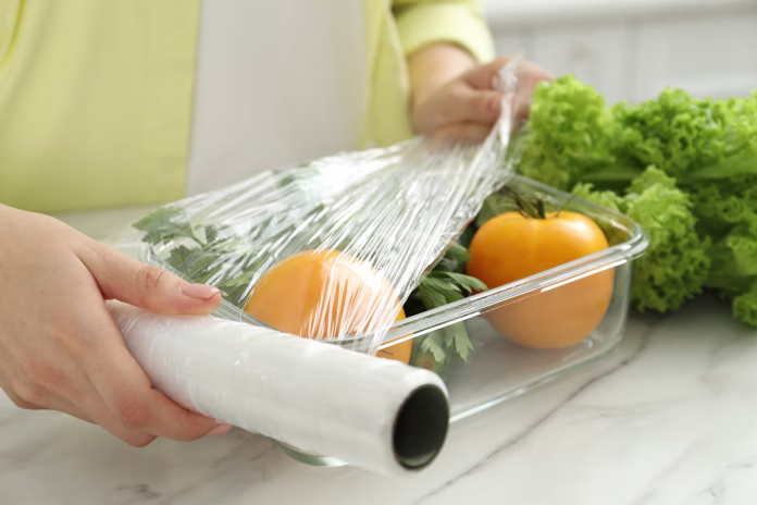 woman-putting-plastic-food-wrap-over-glass-container-with-fresh-vegetables-at-white-marble-table-closeup-stockpack-istock Woman putting plastic food wrap over glass container with fresh vegetables at white marble table, closeup