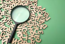 Slovnični nasvet: Velika in mala začetnica za dvopičjem Wooden word and magnifying glass on a green background. Business concept.