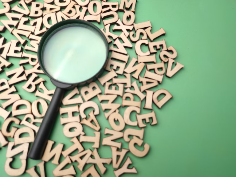 Wooden word and magnifying glass on a green background. Business concept.