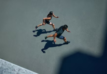Ali hoja porabi več kalorij kot tek? Young, athlete man and woman in sporty attire running together during pair workout on sunny summer day. Fit couple. Concept of sport and healthy lifestyle, pair training, leisure activity.