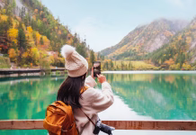 Ideje za krajše jesenske izlete po Sloveniji Young female tourist taking a photo of the beautiful autumn scenery landscape at the Jiuzhaigou national park in Sichuan, China
