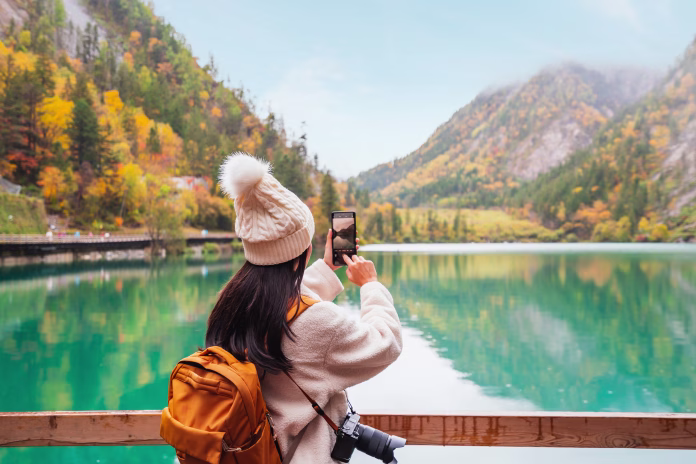 young-female-tourist-taking-a-photo-of-the-beautiful-autumn-scenery-landscape-at-the-jiuzhaigou-national-park-in-sichuan-china-stockpack-istock Young female tourist taking a photo of the beautiful autumn scenery landscape at the Jiuzhaigou national park in Sichuan, China