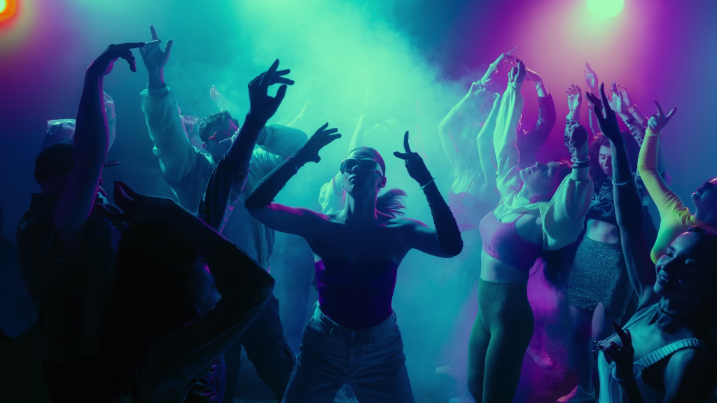 A vibrant party scene with diverse people dancing under colorful lights. Concept of nightlife party, youth, summer, festivity, celebration