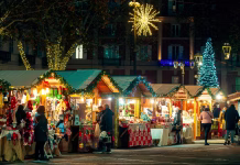 Najboljši božični sejmi v Italiji za leto 2025 Asti, Italy - December 14, 2023: People walking along illuminated wooden kiosk at the Christmas market in Asti - one of the famous and popular annual holiday markets in Italy.