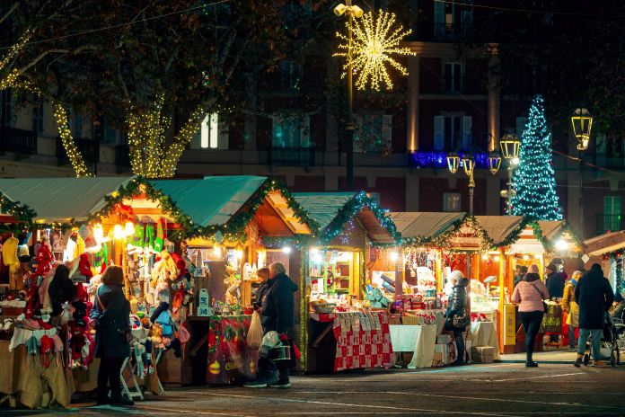 Asti, Italy - December 14, 2023: People walking along illuminated wooden kiosk at the Christmas market in Asti - one of the famous and popular annual holiday markets in Italy.
