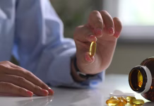 TA oblika vitamina D povezana z negativnimi učinki Close up of hand holding a softgel fish oil capsule. Health and nutrition concept.