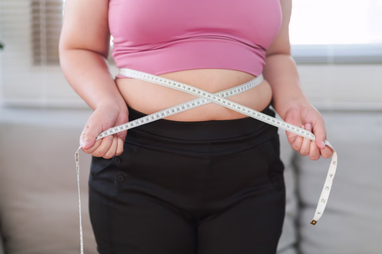 Close up overweight woman measuring her hip with tape measure.