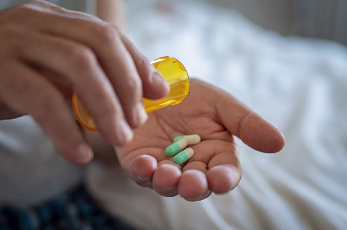 closeup-of-man-hand-pouring-capsules-from-a-pill-bottle-into-hand-senior-man-taking-daily-medicine-to-consume-close-up-of-male-hands-taking-daily-dose-of-drug-stockpack-istock Closeup of man hand pouring capsules from a pill bottle into hand. Senior man taking daily medicine to consume. Close up of male hands taking daily dose of drug.