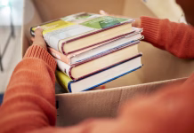 Kako očistiti in razkužiti knjige? (VIDEO) Donation, charity and woman hands with books in box for nonprofit and cardboard container at home. Education textbook, donating and house with giveaway and spring cleaning for community support