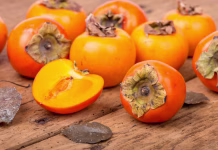 Božanska kaki pita z belo čokolado, ki se stopi v ustih Fresh ripe persimmon on a rough, wooden, rustic table