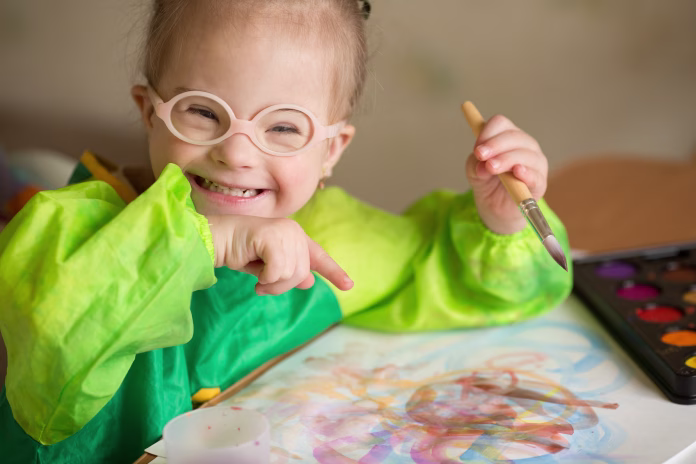 girl-with-down-syndrome-covered-in-paint-when-drawing-stockpack-istock Girl with Down syndrome covered in paint when drawing