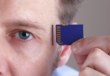 Začelo se je testiranje možganskega vsadka za obnovo govora Inserting SD memory card into slot in human head concept for memory upgrage, forgetfulness or computing