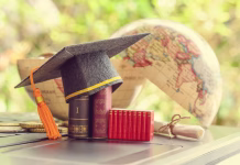 Kaj moraš vedeti, preden se odločiš za doktorat? Key success in graduate study abroad program and open or expand world view experience concept : Graduation cap or hat, certificate or diploma, mini text books on a laptop computer, a half world globe.