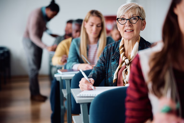 mature-woman-writing-in-notebook-during-adult-education-training-class-in-the-classroom-stockpack-istock