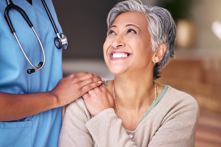 Nurse, senior woman and smile with comfort, holding hands or support in nursing home for retirement. Doctor, medic or caregiver with kindness, empathy or gratitude for help, trust or service in house