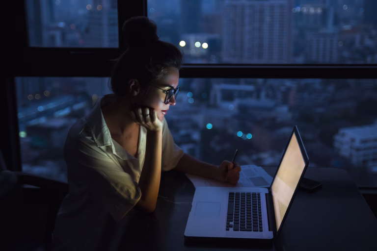 Overtime concept. Woman is working with laptop at home during night.