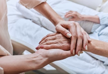 Vesna Ribarič Zupanc: »Naša družba kot celota ni zrela za zakon, ki dopušča pomoč pri smrti« (INTERVJU) Relative holding trembling hand of senior woman with Parkinson's disease lying in hospital bed at medical ward. Diagnosis and treatment of Parkinson's disease and dementia