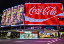 Coca-Cola razjezila z novo reklamo, ustvarila jo je umetna inteligenca Sydney, Australia - March 9, 2017. The Coca-Cola Billboard in Kings Cross, Sydney, with commercial properties and people, at night.
