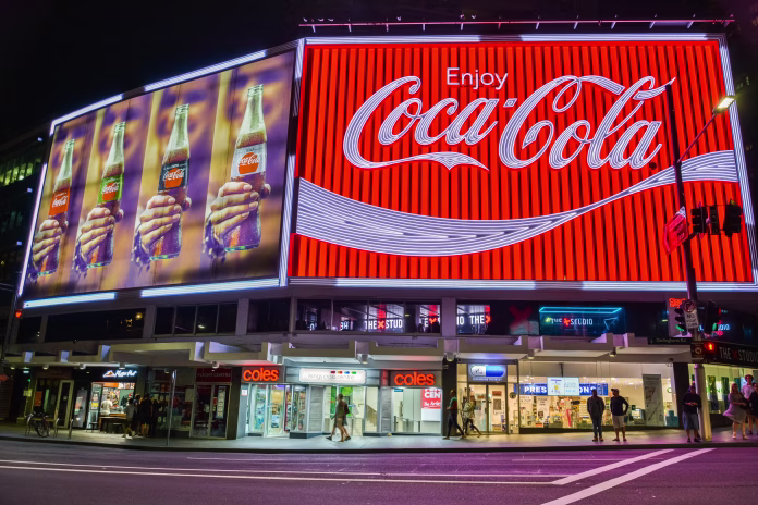 Sydney, Australia - March 9, 2017. The Coca-Cola Billboard in Kings Cross, Sydney, with commercial properties and people, at night.