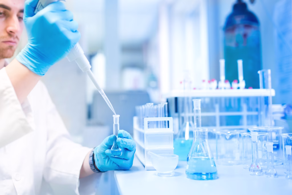 Test tubes in clinic, pharmacy and medical research laboratory with male scientist using pipette