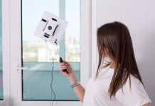 Čiščenje oken z robotom: funkcionira tudi doma? Woman cleaning windows at home with robotic cleaner