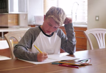 Zakaj je ADHD čedalje pogostejši? Boy child, writing and confused with homework, thinking and process for solution, learning or studying. Kid, paper and problem solving for education, anxiety and notes for development in family house