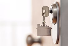 Zaostruje se oddajanje stanovanj: to nas čaka z novim letom Close-up of house key and keychain inserted into a high security door lock. Real estate and home security concept. Copy space.