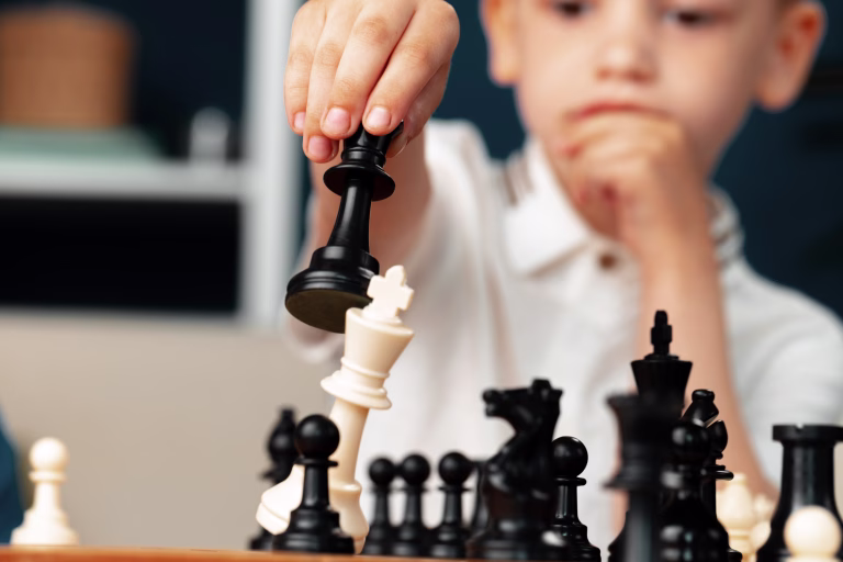 Close up photo of a little boy playing chess, makes a move