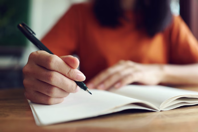 close-up-woman-hand-writing-on-notebook-stockpack-istock Close up woman hand writing on notebook .