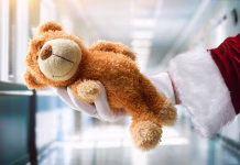 Kako postati darovalec organov po smrti? V Sloveniji se za to odloči zelo malo ljudi Concept of giving toys to hospitalized children at Christmas with Santa Claus's hand wearing a white glove holding a teddy bear in a hospital corridor.
