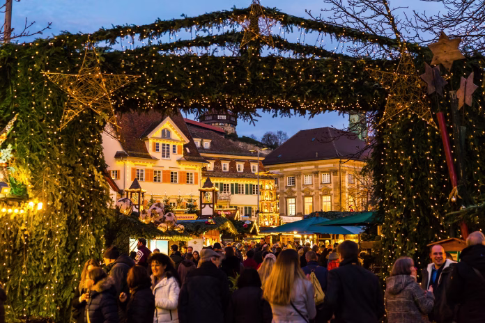 Esslingen am neckar, Germany, December 17, 2019, Entrance gate to christmas market illuminated by night with many people enjoying the beautiful mood