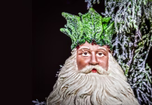 Ali je božič v resnici poganski praznik? Father Christmas - The Holly King - Ceramic Christmas tree decoration with sparkly bokeh greenery background- room for copy.