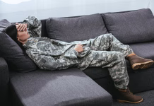 Kako zaspati v 120 sekundah? female soldier in military uniform with ptsd lying on couch