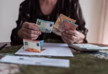 Zakaj bodo pokojnine letos izplačane kasneje? Je kriv zimski dodatek … Finances, savings, annuity insurance and people concept - senior woman with calculator and bills is counting money at home. Senior woman is calculating taxes at home.Counts the pension.
