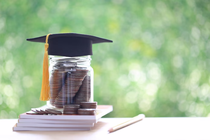 Graduation hat on coins money in the glass bottle on natural green background, Saving money for education concept