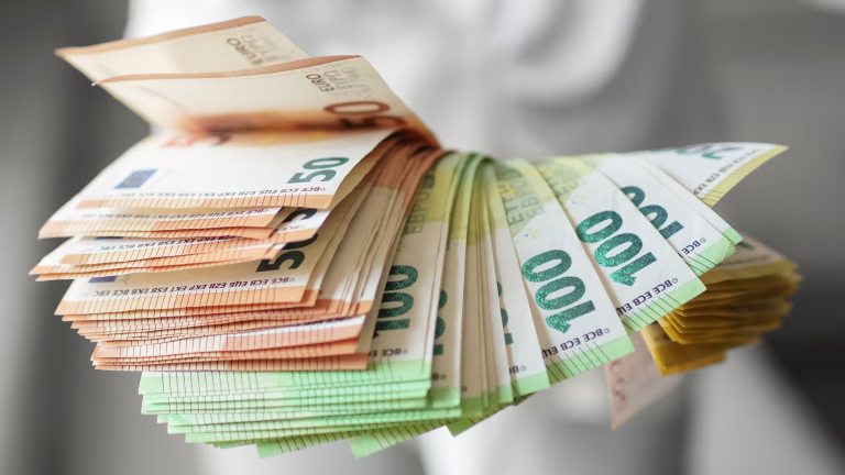 Hand holding large fan of euro banknotes in 50, 100, and 200 denominations, concept of abundance, wealth, success and financial prosperity