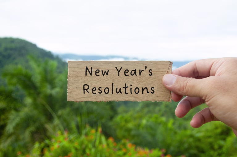 Hand holding wooden block with New Year's Resolution text with beautiful nature background.