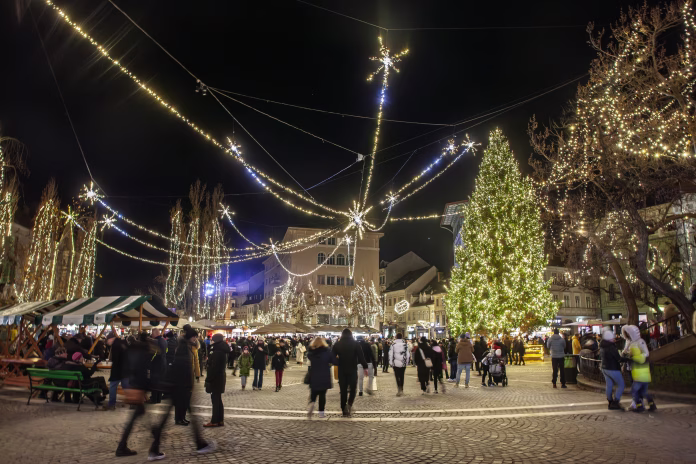Ljubljana, Slovenia - December 17, 2024: Nighttime image capturing the vibrant atmosphere of Ljubljana's annual Christmas market in Preseren Square (Presernov trg), Slovenia. The scene features a beautifully decorated Christmas tree, festive lights, seasonal decorations, and bustling crowds enjoying holiday shopping and celebrations. This festive event embodies Slovenian traditions, attracting locals and international tourists for seasonal festivities.