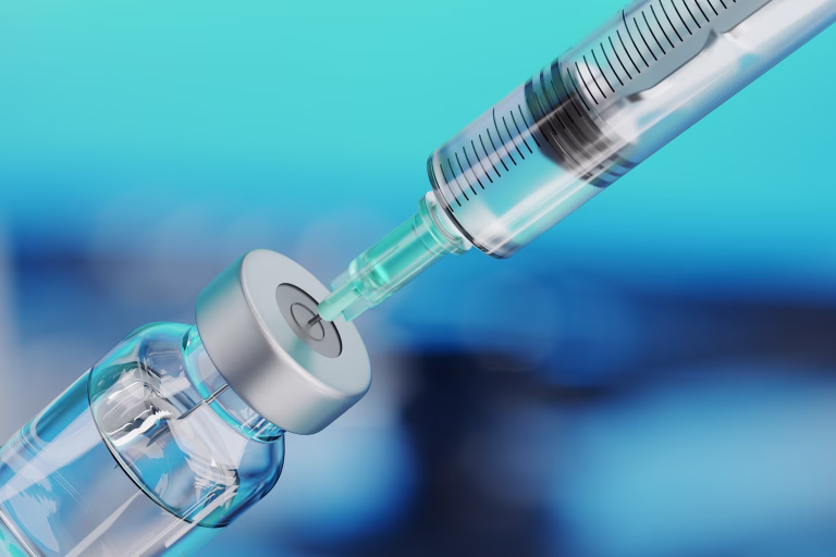 Medical disposable syringe for vaccine injection and glass vial on blue blur background.